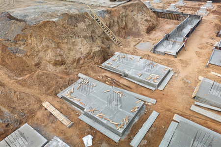 A group of concrete blocks gracefully arranged on a dirt field, forming reinforced foundations in a construction site.の写真素材