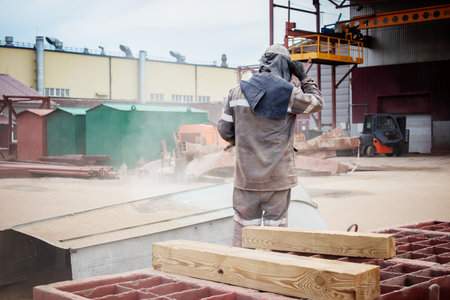 A worker uses sandblasting equipment to effectively remove rust from a metal structure at an industrial plant, ensuring the integrity of the materials.の写真素材