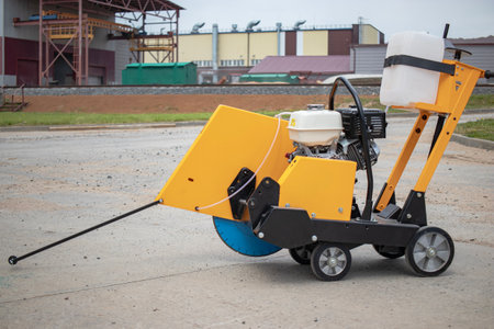 A concrete cutting machine is actively dismantling road surfaces at a construction site in bright daylight, showing its robust design and functionality.の写真素材