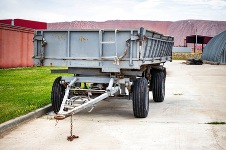 A large cargo trailer parked on the side of a quiet road, its massive frame casting a shadow in the...