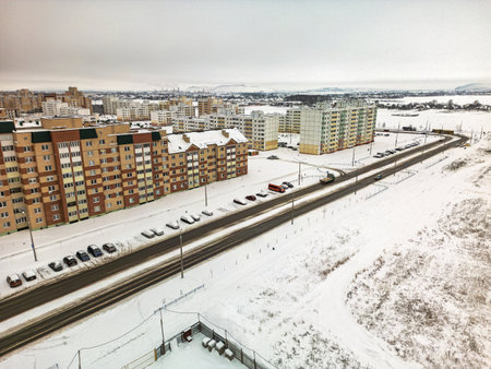 The view captures a snowy urban neighborhood with apartment buildings lining the road in winter.の写真素材