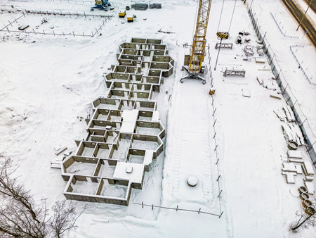 New building foundations are emerging in a snowy construction site with machinery and materials visible in a city environment.の写真素材