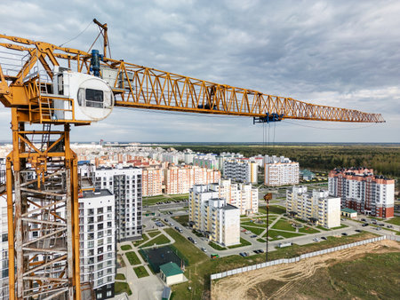 The crane moves efficiently, lifting heavy materials while overseeing the vibrant development of modern housing in the landscape.の写真素材