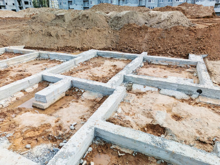 Workers lay the foundation for a new building, with concrete blocks amidst dirt and gravel at the construction site.の写真素材
