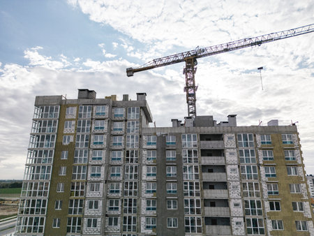 Cranes tower over a new residential building, showcasing the city's busy construction scene.の写真素材