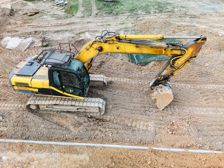 The excavator skillfully digs into the ground, reshaping the landscape at a bustling construction site under clear blue skies.の写真素材