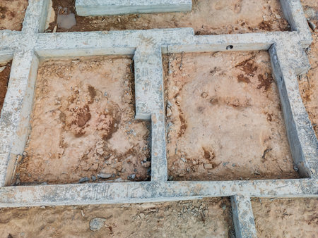 Workers prepare foundations at a construction site, showcasing unique patterns on the exposed dry soil under bright sunlight.の写真素材