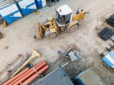 A large machine drives through a bustling construction site filled with building materials and containers.の写真素材