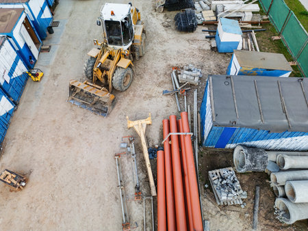 Heavy machinery is at work, surrounded by neatly arranged construction materials on an active industrial site during daylight.の写真素材