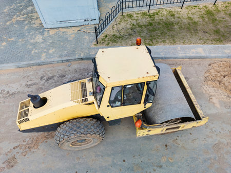 A bulldozer paves the way for progress in a busy urban environment, surrounded by soft earth under the clear sky.の写真素材