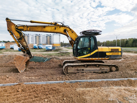 A large yellow excavator works diligently on a construction site, leveling the furrowed earth on a cool, overcast morning.の写真素材