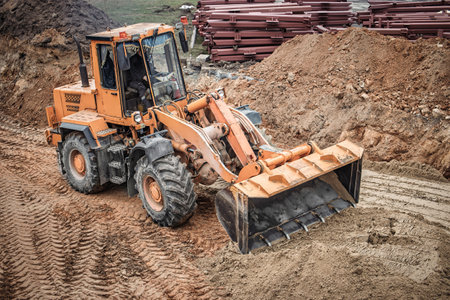 A powerful loader maneuvers through the earth, expertly preparing the site for upcoming construction activities in broad daylight.の写真素材