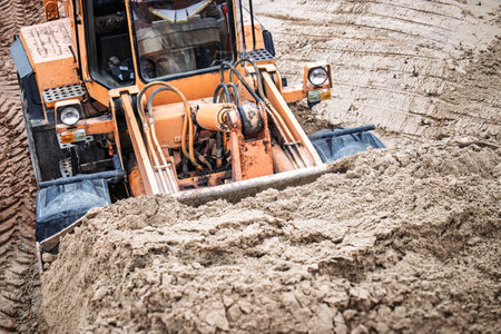 A bulldozer digs and moves sand, showcasing the impressive power of construction machinery in action.の写真素材