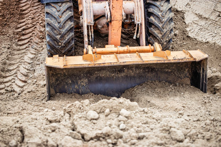 A bulldozer skillfully levels the ground, showcasing the focus needed for construction under clear...