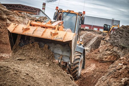 Heavy machinery works diligently to move dirt and shape the landscape at a construction site,...