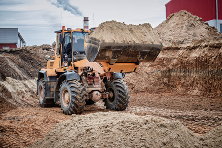 A large loader scoops sand at a construction site, demonstrating the power of machinery in shaping the landscape.の写真素材