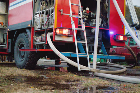 A fire truck stands ready, hoses connected, as water reflects the vibrant colors of the vehicle....