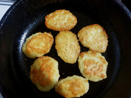 Golden-brown pancakes sizzle in a black skillet, capturing the warmth of a sunny morning. The inviting aroma fills the cozy kitchen, sparkling joy and hunger.の写真素材