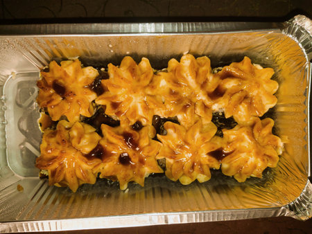 A tray brims with delicately crafted flower-shaped desserts topped with rich caramel sauce, enchanting everyone at a vibrant local celebration.の写真素材