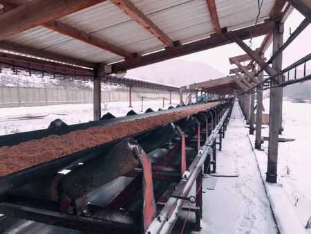 A lengthy conveyor belt stretches across the snowy terrain, efficiently moving materials at a mining site in a remote area, showcasing winter's icy beauty.の写真素材