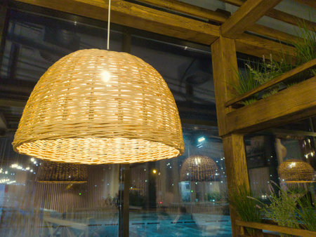 A beautiful wicker light fixture casts a soft, warm light, enhancing the inviting atmosphere of the modern interior. The design blends nature with elegance at sunset.の写真素材