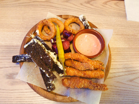 A vibrant platter of crispy appetizers features golden fried strips, onion rings, and tangy pickles, inviting patrons to indulge in a flavorful experience.の写真素材