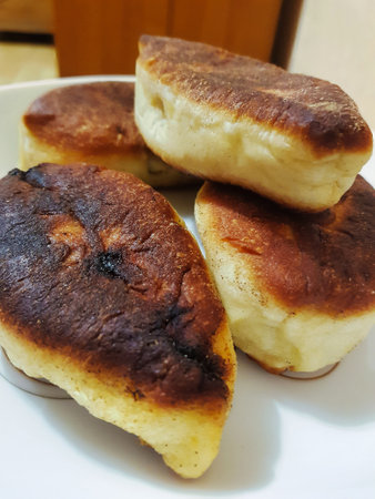 Golden-brown pastries sit invitingly on a white plate, showing a crispy exterior. Their soft, warm filling promises a delightful taste experience.の写真素材