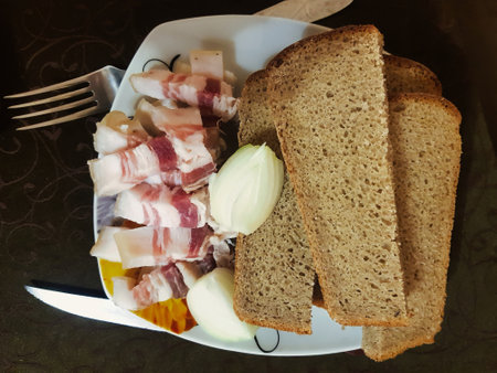 A delightful array of cured meat pieces and sliced dark rye bread on a decorative plate captures the essence of a cozy evening gathering with friends.の写真素材