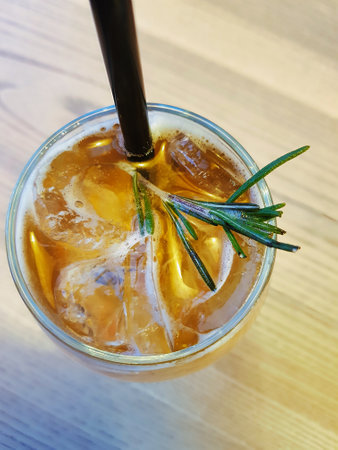 A delightful drink features rosemary sprigs floating atop ice cubes in a clear glass, showing a refreshing blend perfect for warm afternoons.の写真素材