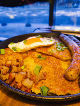 A tempting breakfast features savory sausage, fluffy pancakes, a sunny-side-up egg, and fresh green onions in a warm setting.の写真素材
