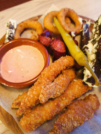 A mouthwatering assortment of crispy fried snacks is beautifully arranged on a rustic wooden platter.の写真素材