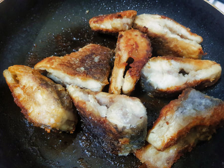 Crispy fish fillets are being pan-fried to perfection, emitting mouthwatering aromas that fill the kitchen during a vibrant afternoon culinary adventure.の写真素材