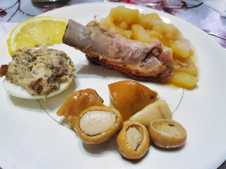 A plate showcases a variety of flavors, featuring succulent meat, seasoned vegetables, a zesty lemon slice, and a unique egg dish, inviting a delightful culinary experience.の写真素材