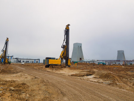 Heavy machinery works diligently to install deep foundations as morning light breaks over the construction site, ensuring stability for upcoming structures.の写真素材