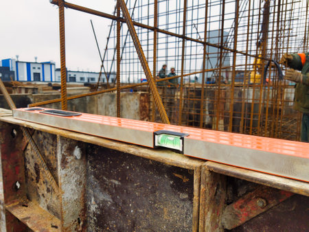 Early morning at a bustling construction site where workers focus on accuracy. A leveling tool rests...