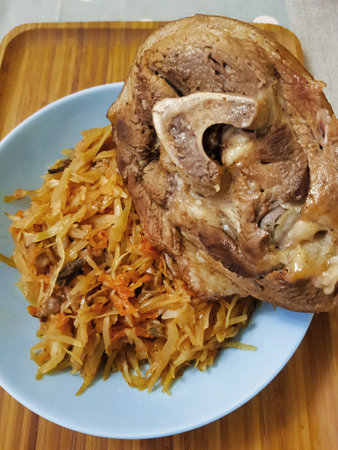 A plate showcases tender slow-cooked meat beside a generous portion of stir-fried vegetables, highlighting delicious textures and rich flavors in a warm kitchen.の写真素材