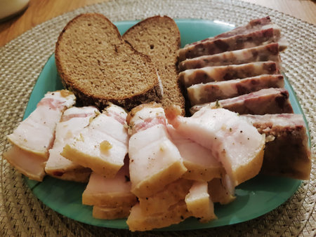 A delightful assortment of smoked meats is presented alongside slices of hearty dark rye bread, inviting a sense of warmth and togetherness on a rustic table.の写真素材