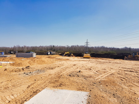 Heavy machinery works tirelessly on a construction site surrounded by nature, showing progress in a rural setting. Clear skies and distant tree lines set the backdrop.の写真素材