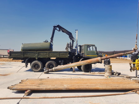 A large truck equipped with a crane chassis stands at a construction site, actively engaging in...