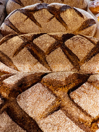 Rows of artisan bread loaves are presented in a local bakery, showcasing their golden crust and...