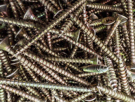 A chaotic collection of screws in different sizes and shapes is spread across a workbench,...