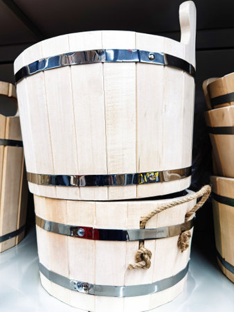 Multiple wooden buckets are neatly arranged on display, featuring natural wood finishes with shiny metal bands. Some have handles made from rope for easy carrying.の写真素材
