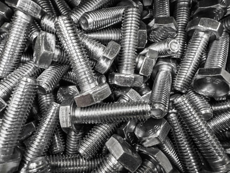 A collection of steel bolts lies scattered, revealing their intricately threaded surfaces and hexagonal heads.の写真素材