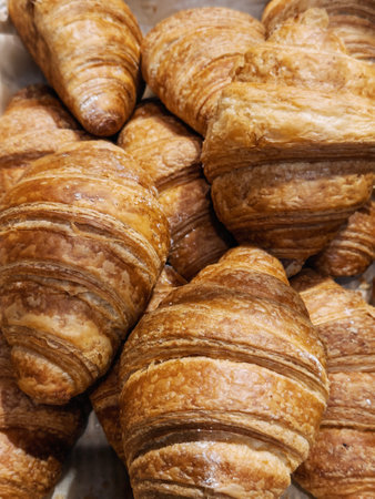 Croissants are freshly baked and displayed in a bakery, showcasing their golden, flaky layers,...