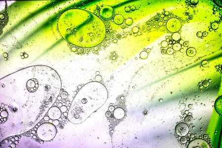Colorful bubbles and flowing patterns emerge under a microscope, revealing an abstract landscape filled with vibrant hues and dynamic shapes in motion.の写真素材