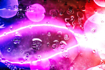 Colorful bubbles and fluid shapes interact under a microscope, creating an enchanting display of abstract art in vibrant hues and glowing contrasts.の写真素材