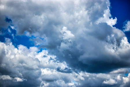 Fluffy clouds billow across the sky, blending shades of gray and white against a vibrant blue...