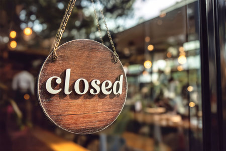 A round wooden closed sign is prominently displayed on a glass cafe door, conveying that the establishment is currently not open for business.の素材