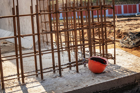Workers prepare a framework of rebar for a building project while tools and materials are arranged...