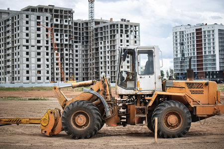 Heavy machinery is actively engaged in construction at a site with multiple buildings underway,...